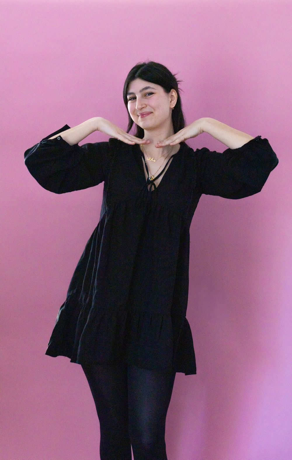 A figure in a black outfit poses against a pink background in a series of dynamic dance-like movements.