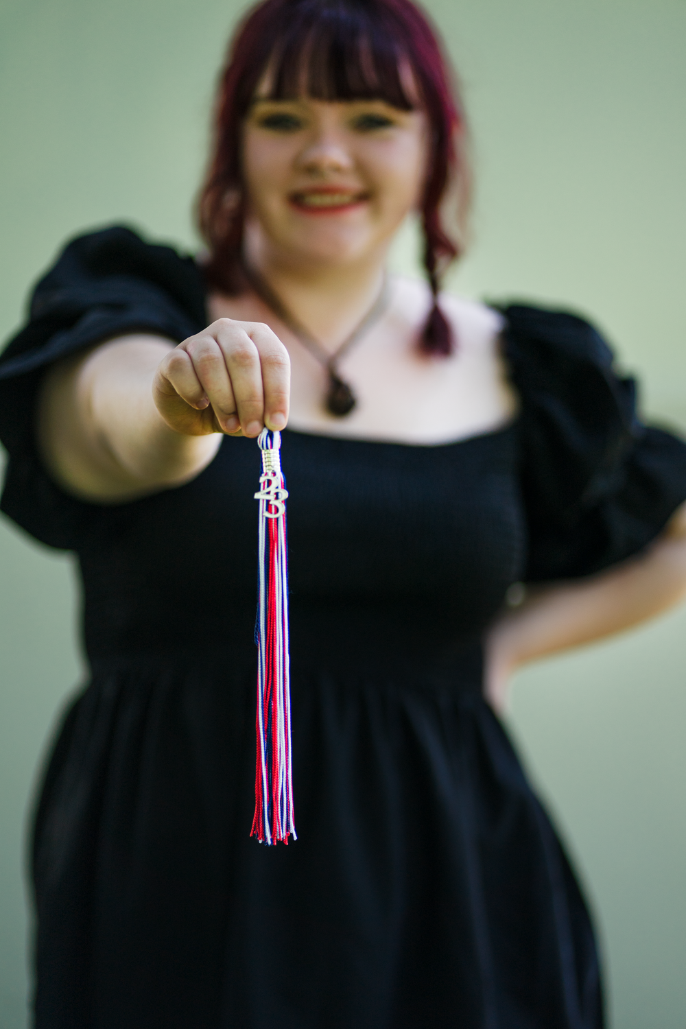 A person in a black dress holds up a small decorative tassel in a sequence of progressive motion shots.