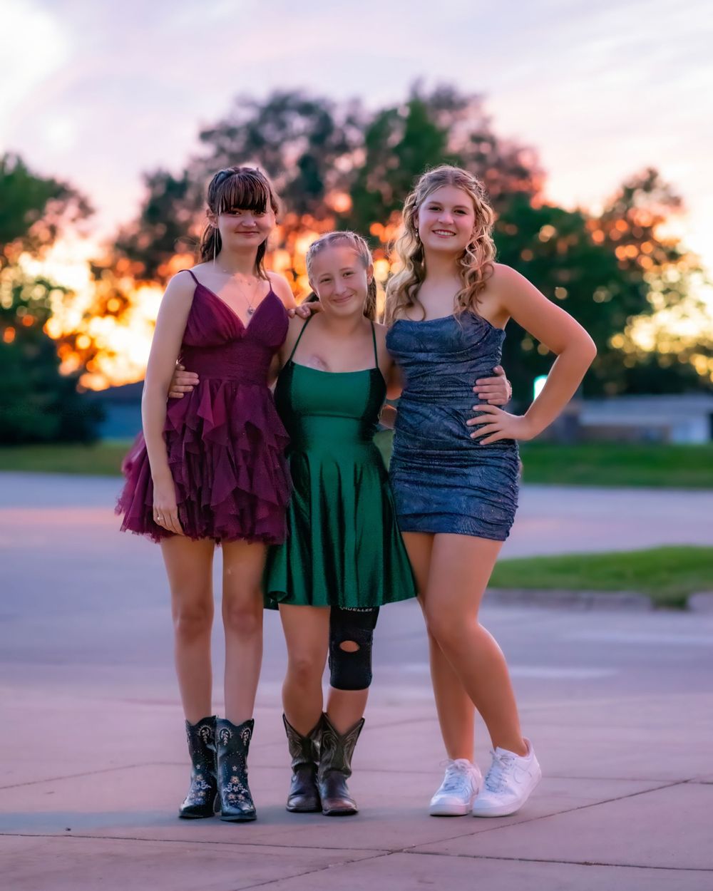Three pairs of boots and shoes visible against a sunset sky during an outdoor summer photo shoot.