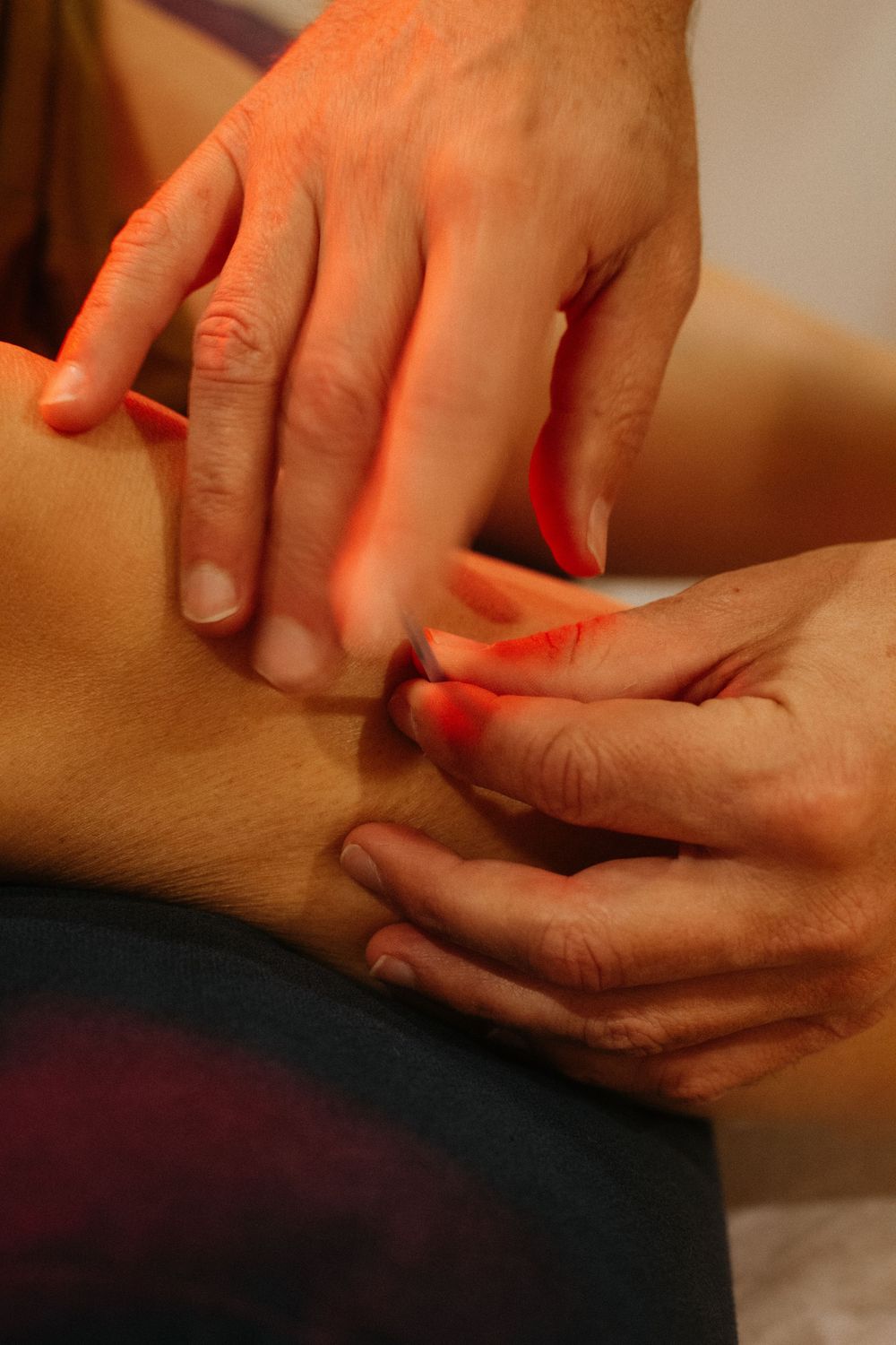 Detail photograph of acupuncturist whilst inserting a needle into the foot of a client in their studio in Portland, Maine.