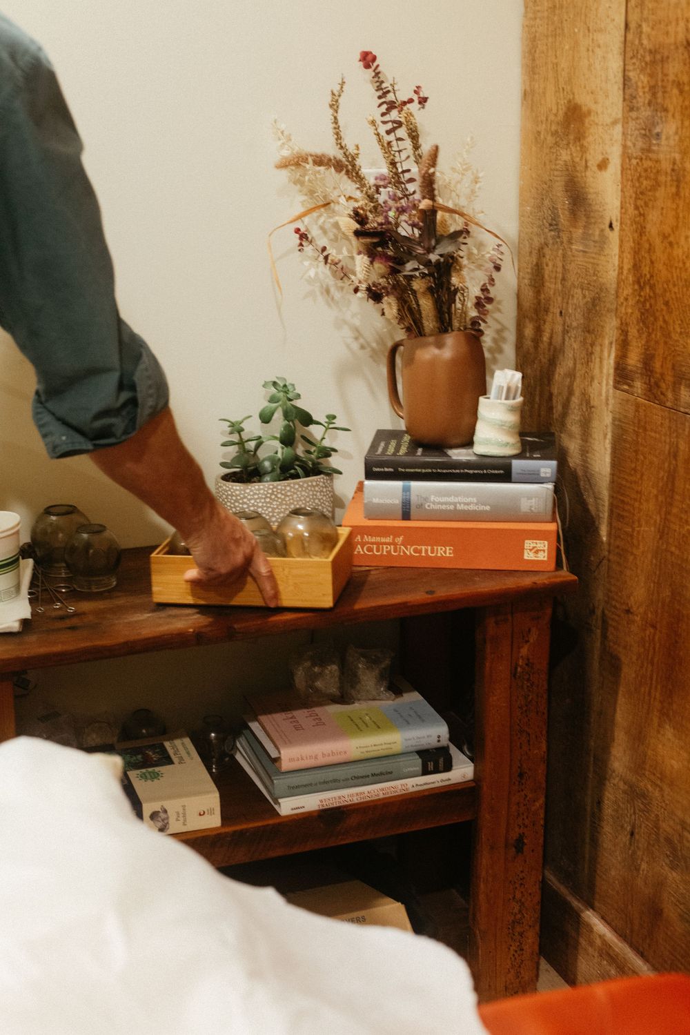 Decorative shelf in acupuncture studio displaying books and dried flowers and cupping tools in their small local business in Portland, Maine