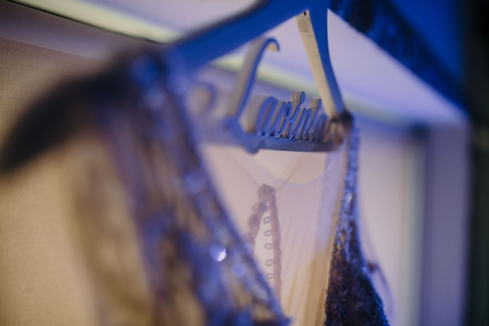 Custom laser-cut wedding dress hanger with bride's name displayed elegantly in blue lighting.