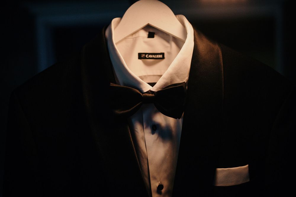 Elegant black tuxedo with white dress shirt and bow tie displayed on a mannequin.