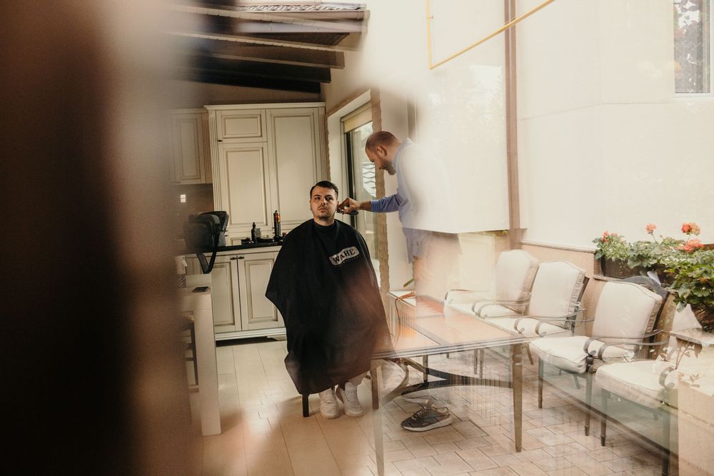 Groom getting haircut reflected in mirror inside elegant bright interior space.