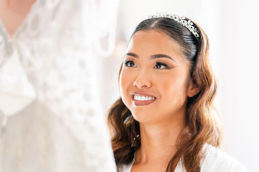 Smiling Asian bride wearing a crystal tiara headband with elegant hair styling on her wedding day.