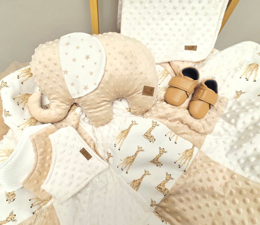 Neutral beige baby nursery set with giraffe print blanket, elephant pillow, star fabric, and tan leather booties.