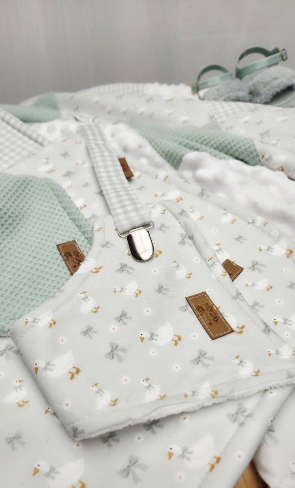 Soft baby bedding set featuring white floral fabric with dragonflies, mint green waffle texture, and gingham accents with leather labels.