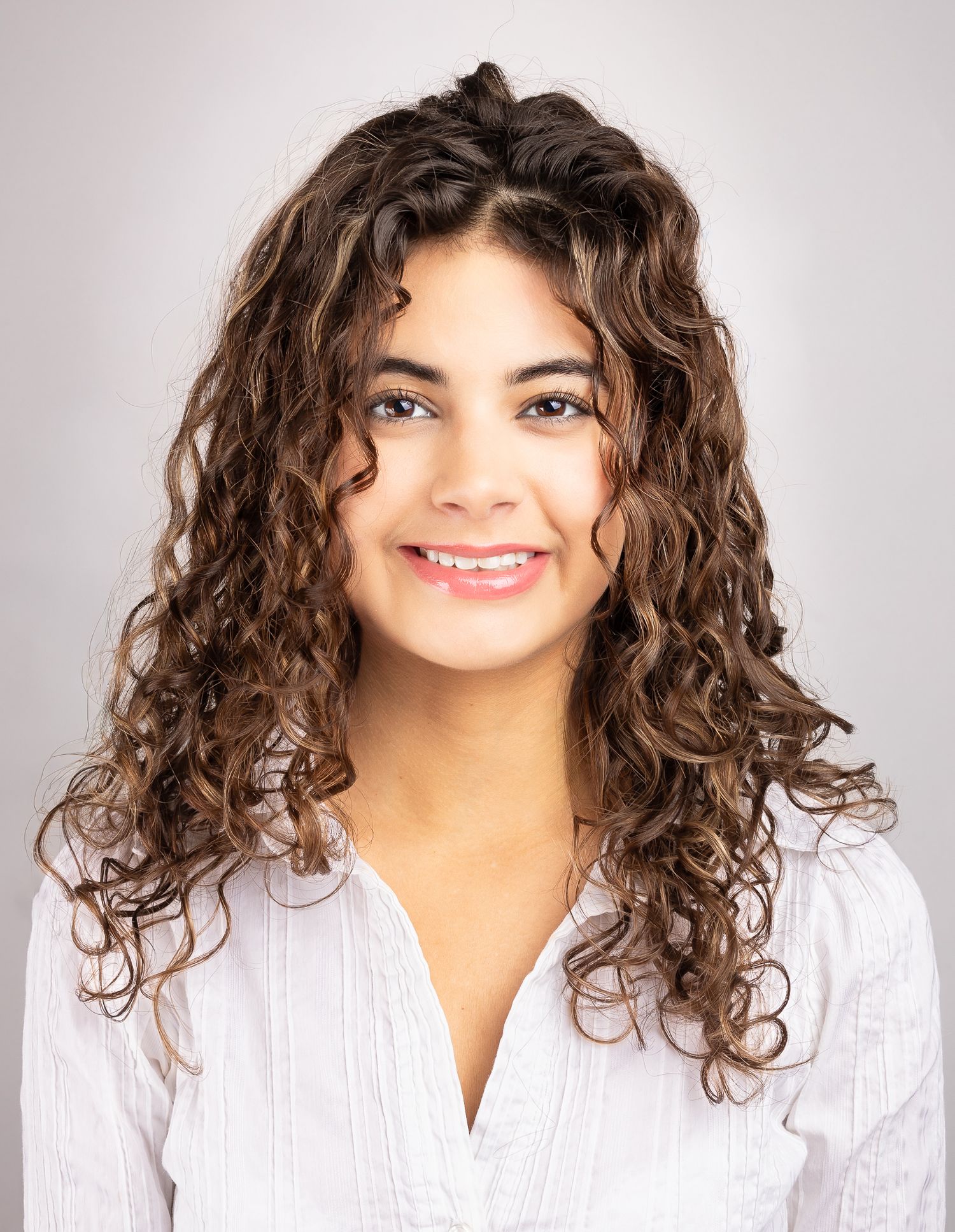 Headshot portrait of a girl in front of a white backdrop, smiling and laughing