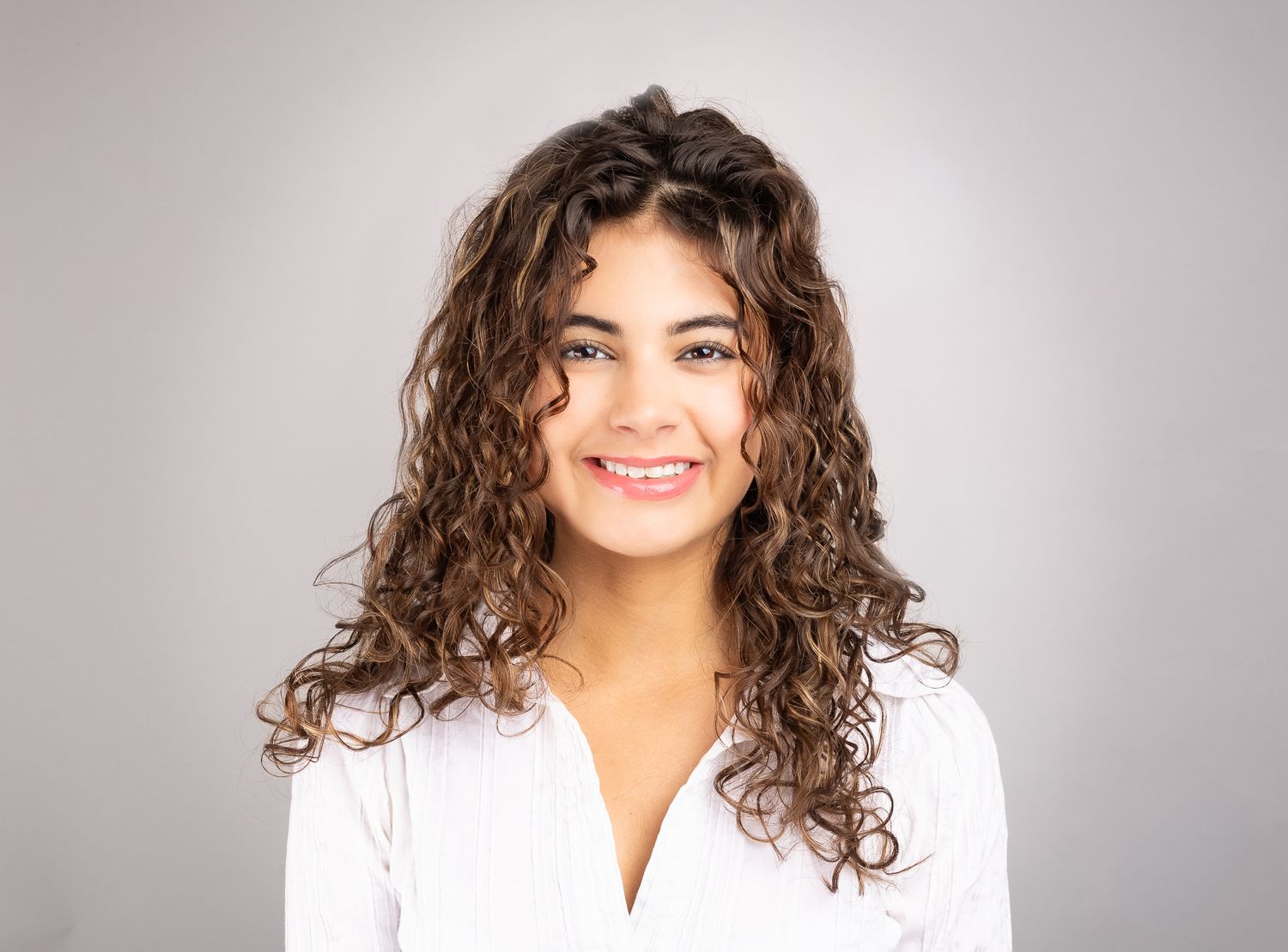 Landscape portrait of a girl in front of a white backdrop, smiling and laughing