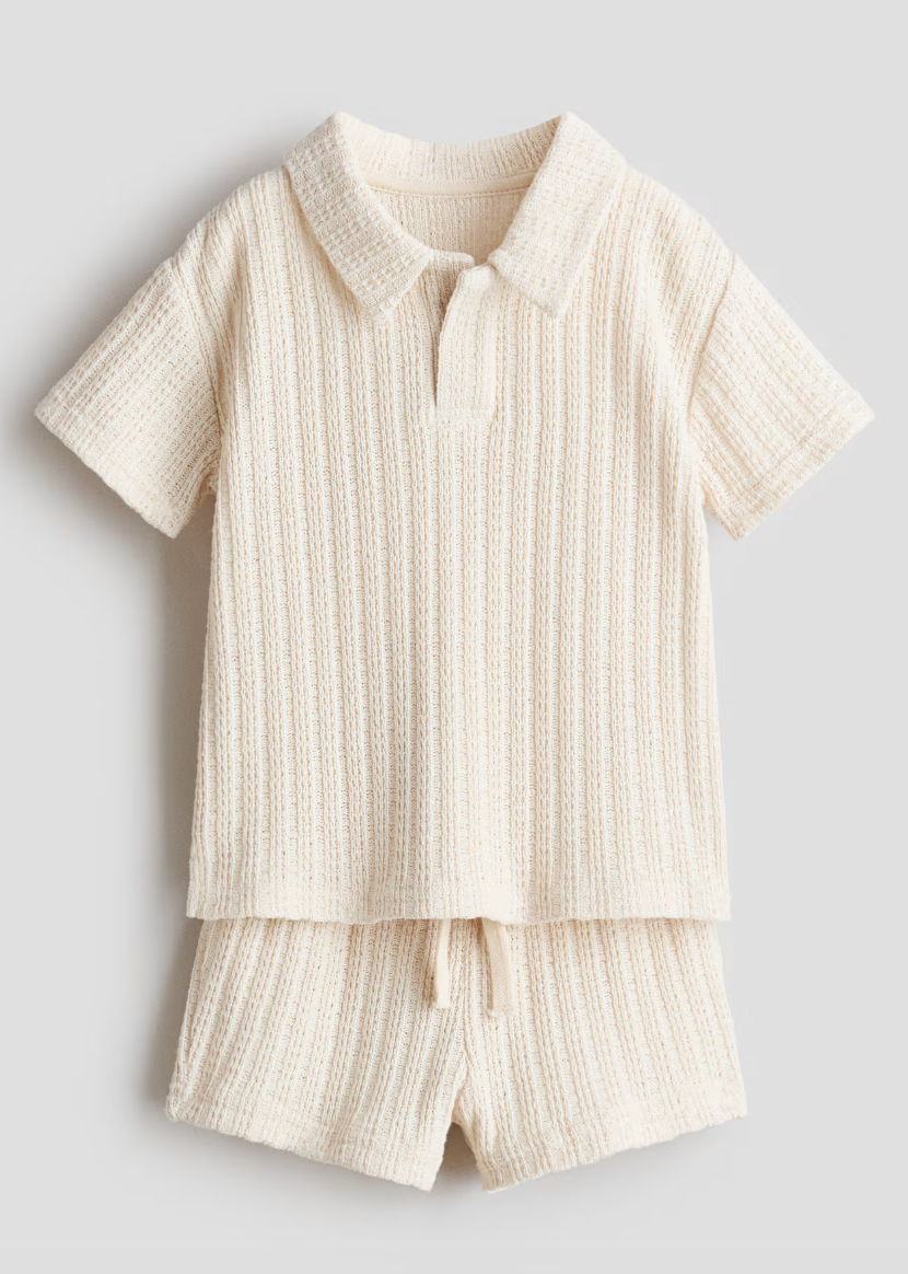 Cream knit polo shirt and shorts set for babies featuring ribbed texture, collar neckline, and drawstring waist.