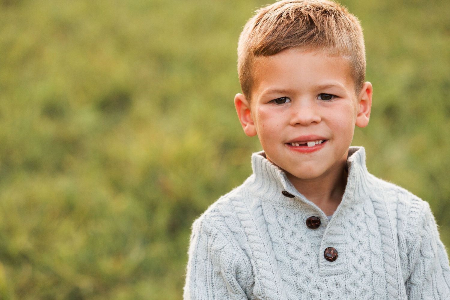 A series of candid outdoor portrait shots showing joyful expressions and a cozy white knit sweater against green grass.