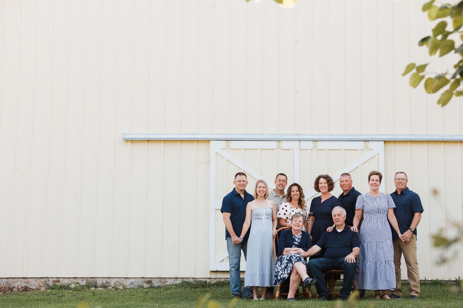 A group of people wearing coordinated blue and white outfits pose together in front of a white barn wall.