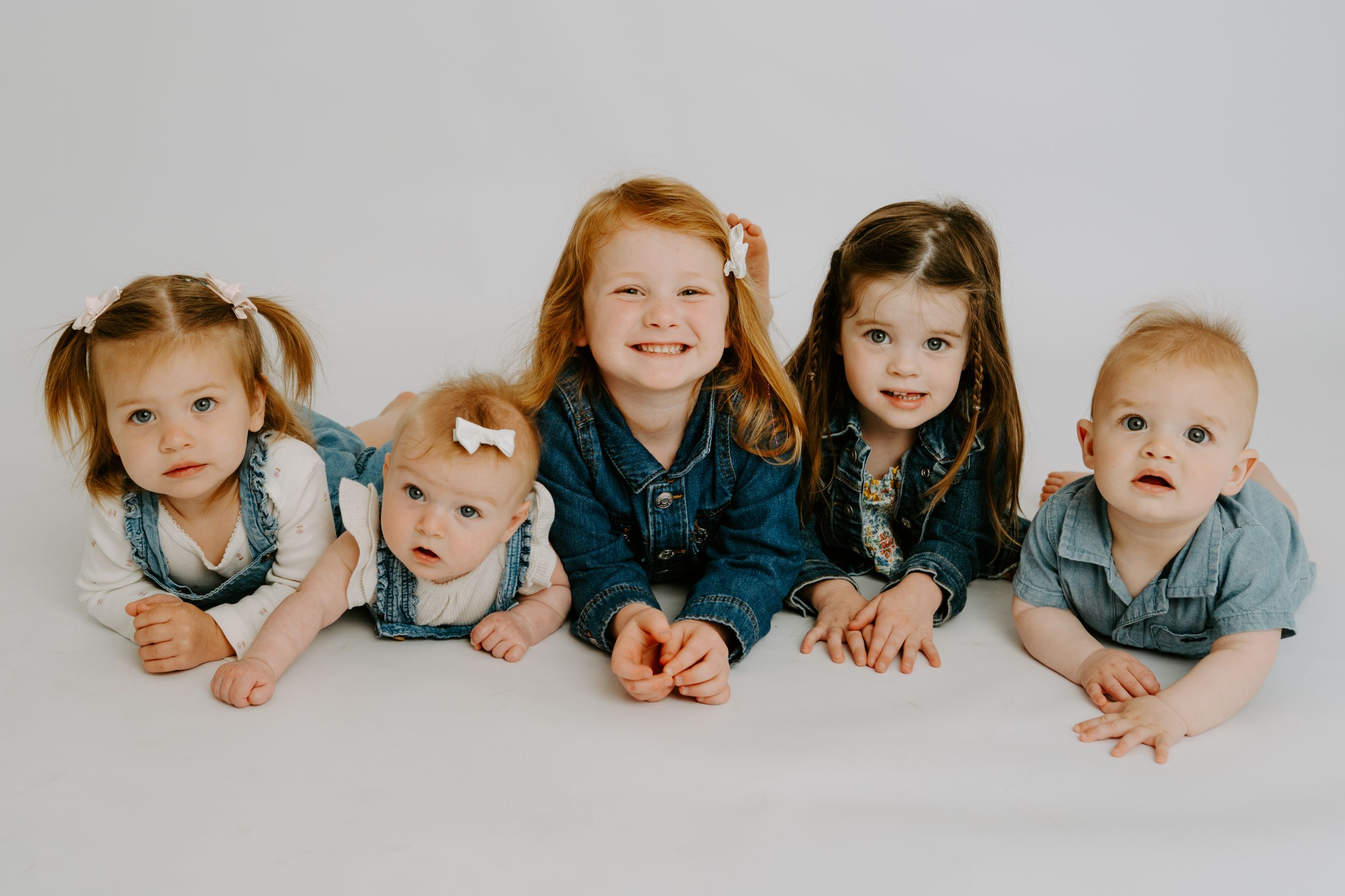 Five young children posing together on a white background, smiling for a professional portrait photo.
