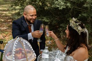 Bride and groom toasting with champagne glasses at an outdoor woodland wedding celebration.