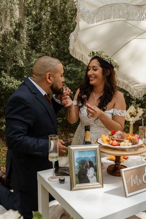 Smiling bride and groom sharing a moment at their decorated outdoor wedding reception table.