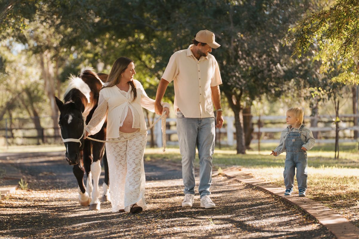 Family walking with a pony on a sunny farm path, enjoying a peaceful outdoor stroll during a maternity photoshoot in Sydney near Rouse hill