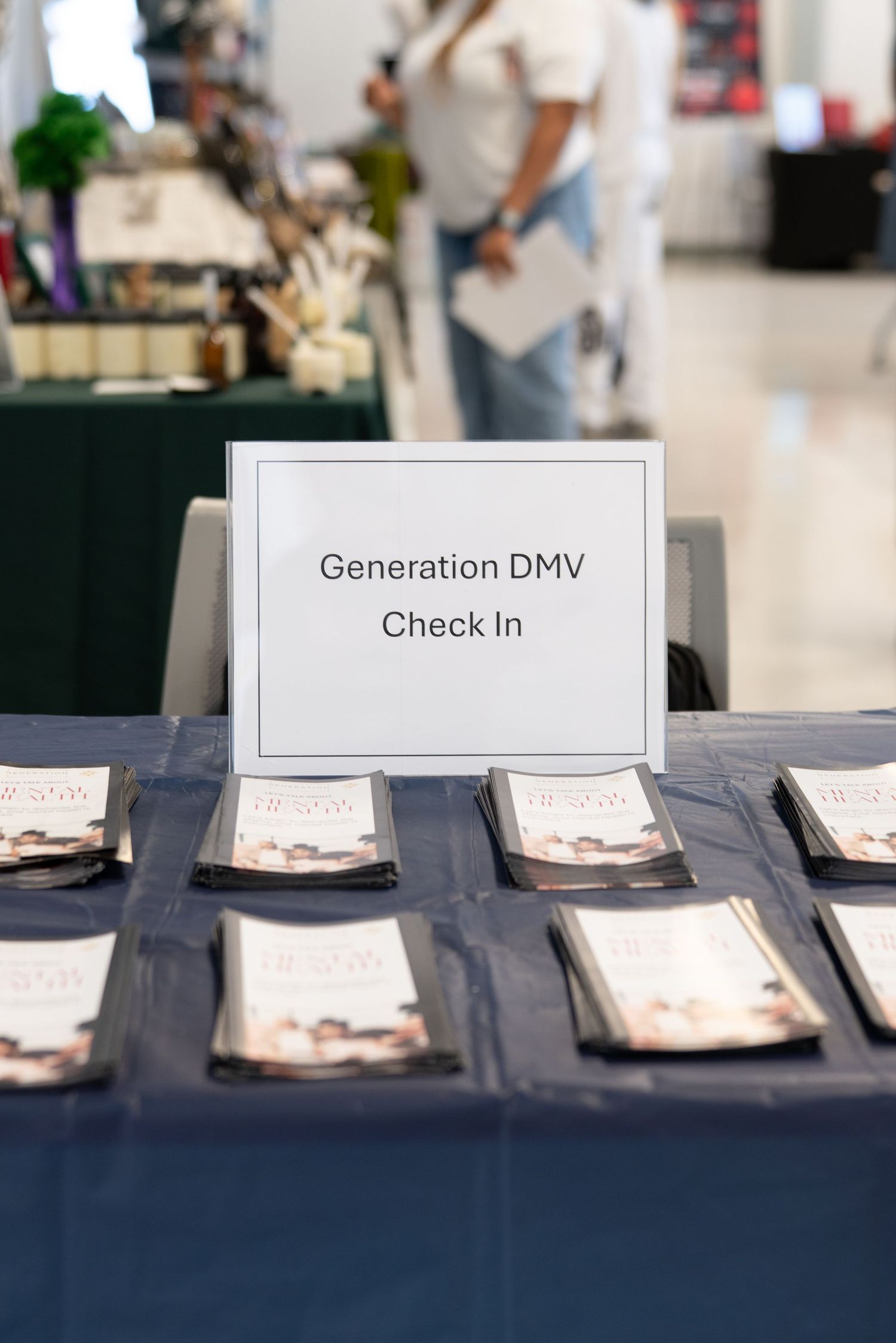 Generation DMV Check In table with brochures at a registration event in a bright indoor venue.