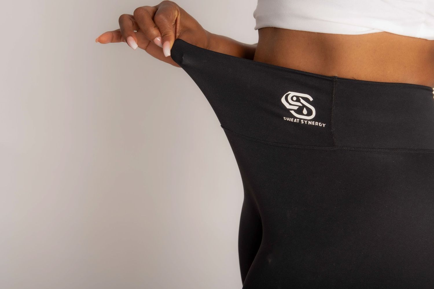 Close-up of black athletic leggings with a logo waistband, worn by a person holding the waistband out.