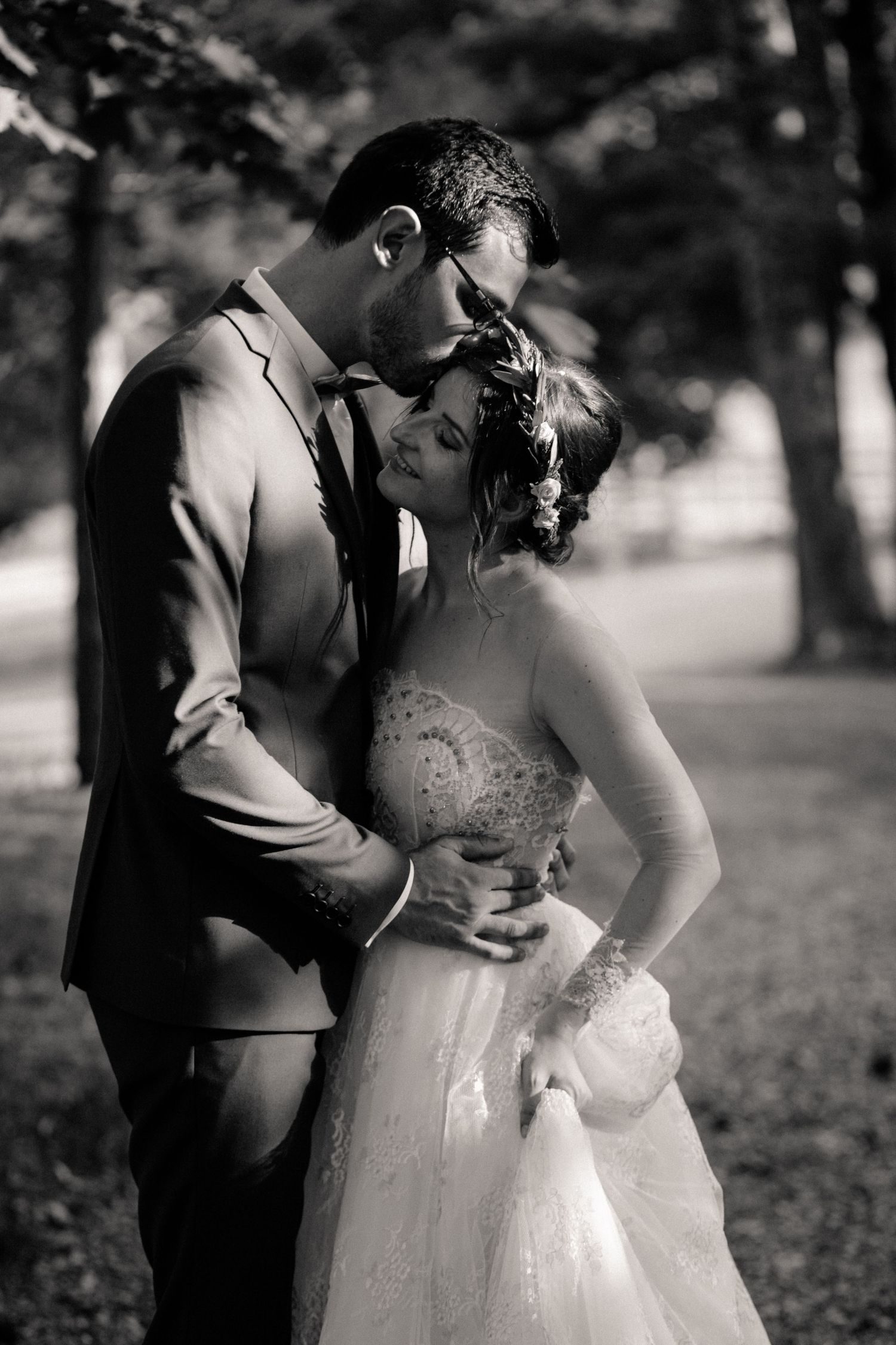 Bride and groom pose before grand stone mansion with ivy-covered facade and tall windows.