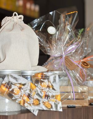 Assorted spa gift sets with linen bags, cellophane wrapping, and enjoy your glow branding displayed.