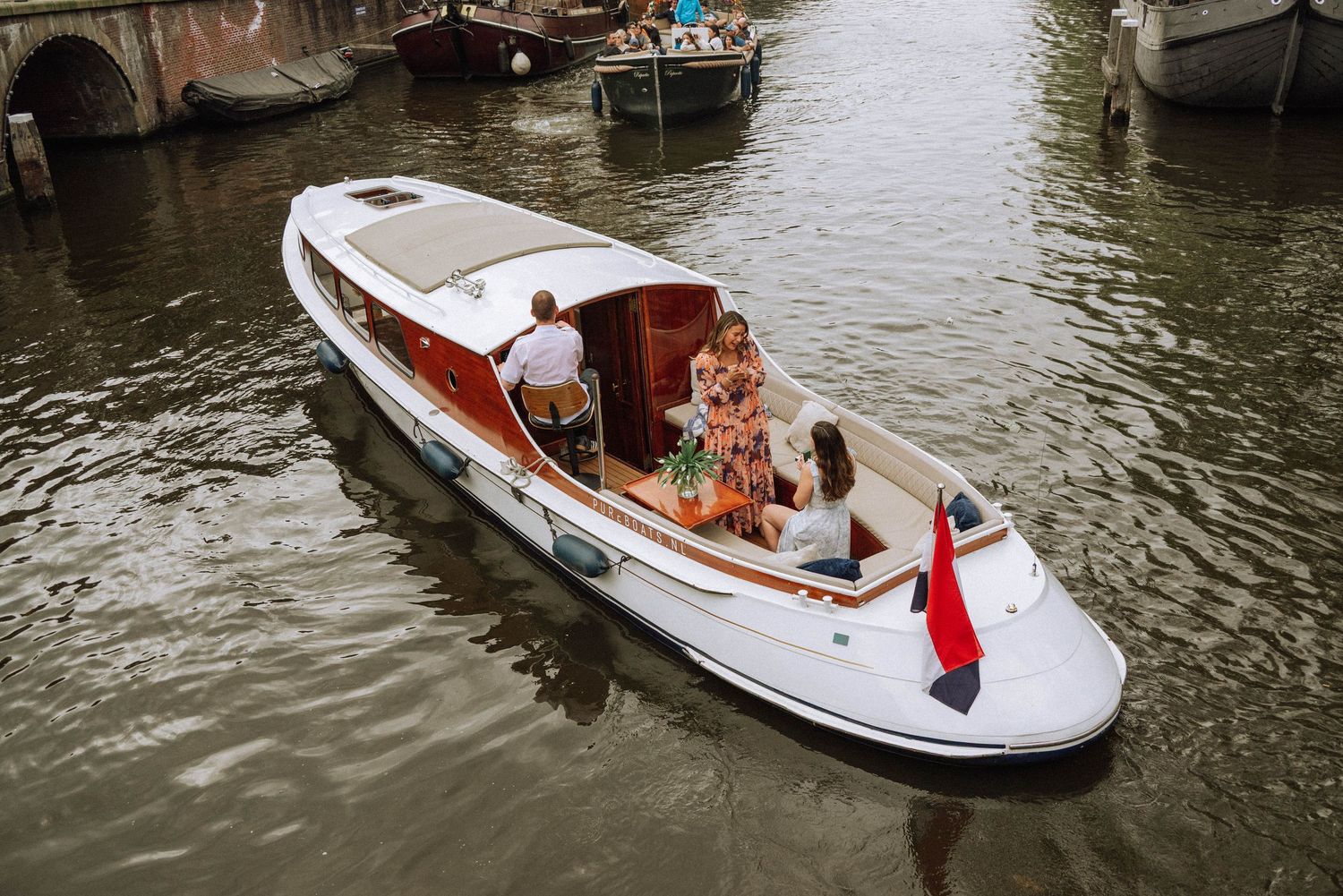 Couple during secret proposal knee moment - Amsterdam canal in a classic white wooden sloop.