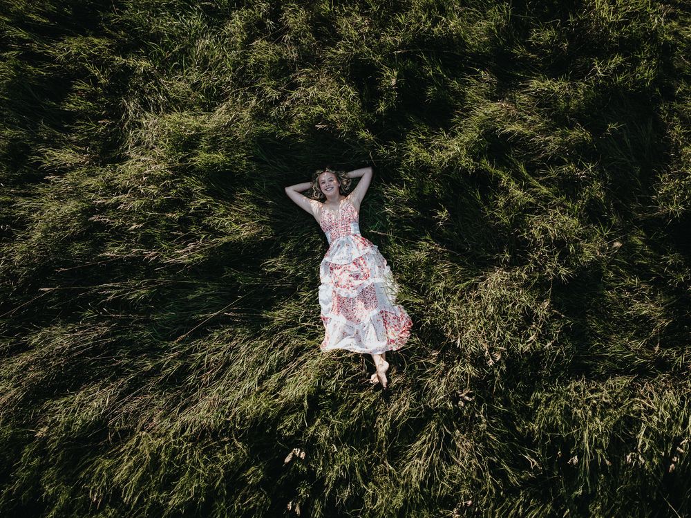 A series of wedding dress photos showing a flowing white gown against a backdrop of lush green trees and foliage.