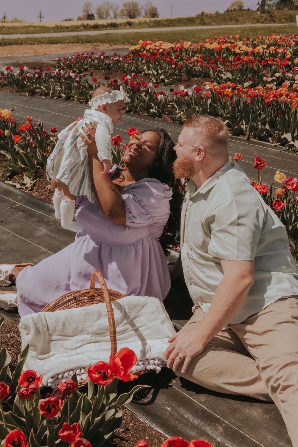 A family shares joyful moments among vibrant red tulips in a garden setting.