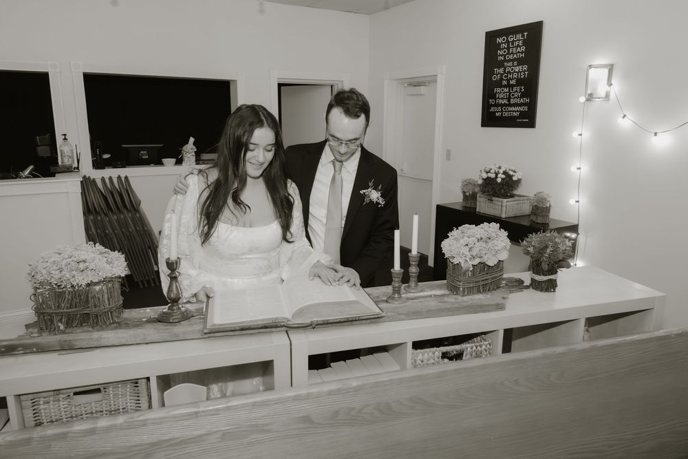 Black and white panoramic photo of a wedding reception showing tables and guests in an elegant venue.