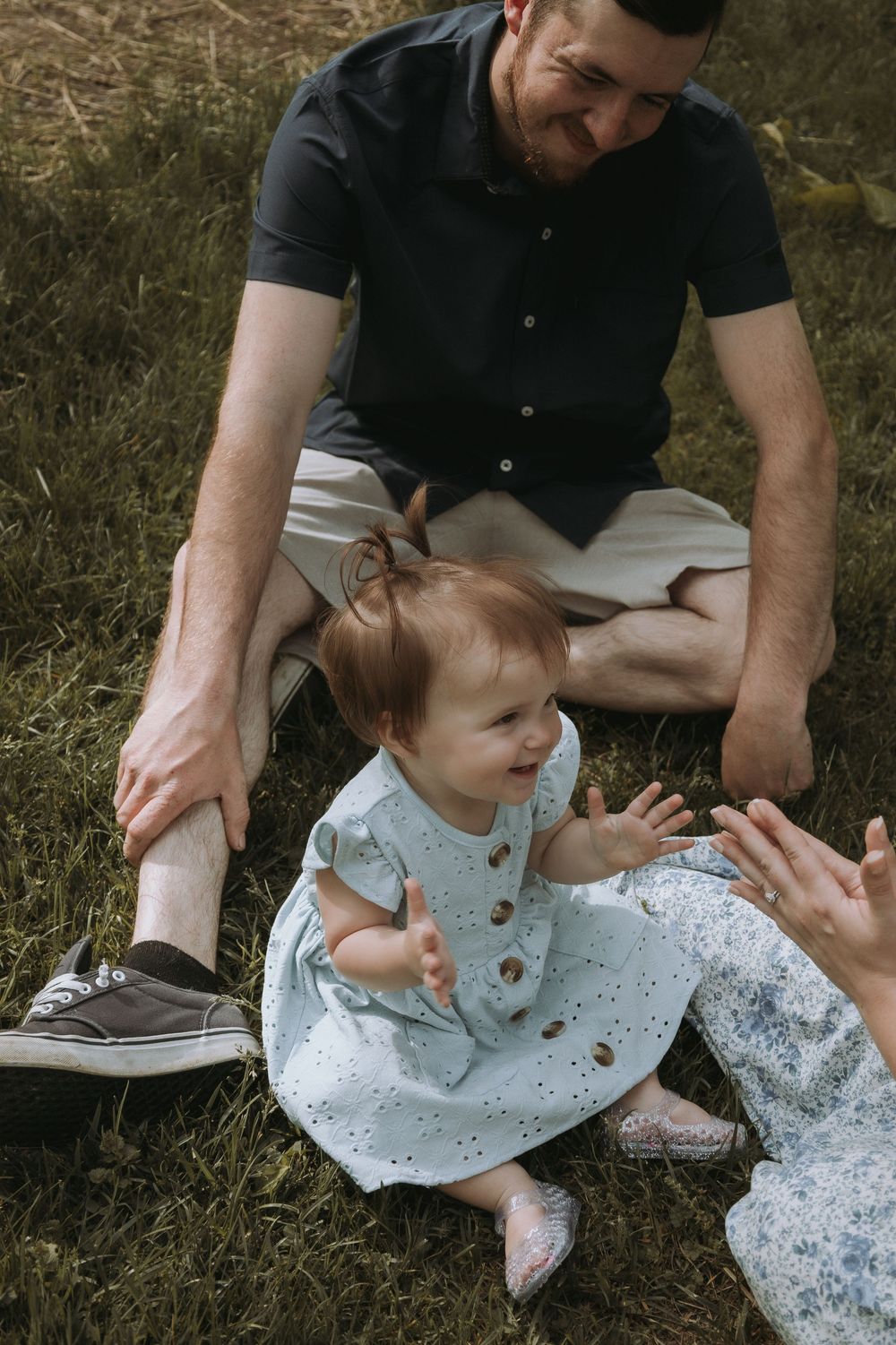 Natural outdoor photography sequence showing gentle interactions on grass in warm sunlight.