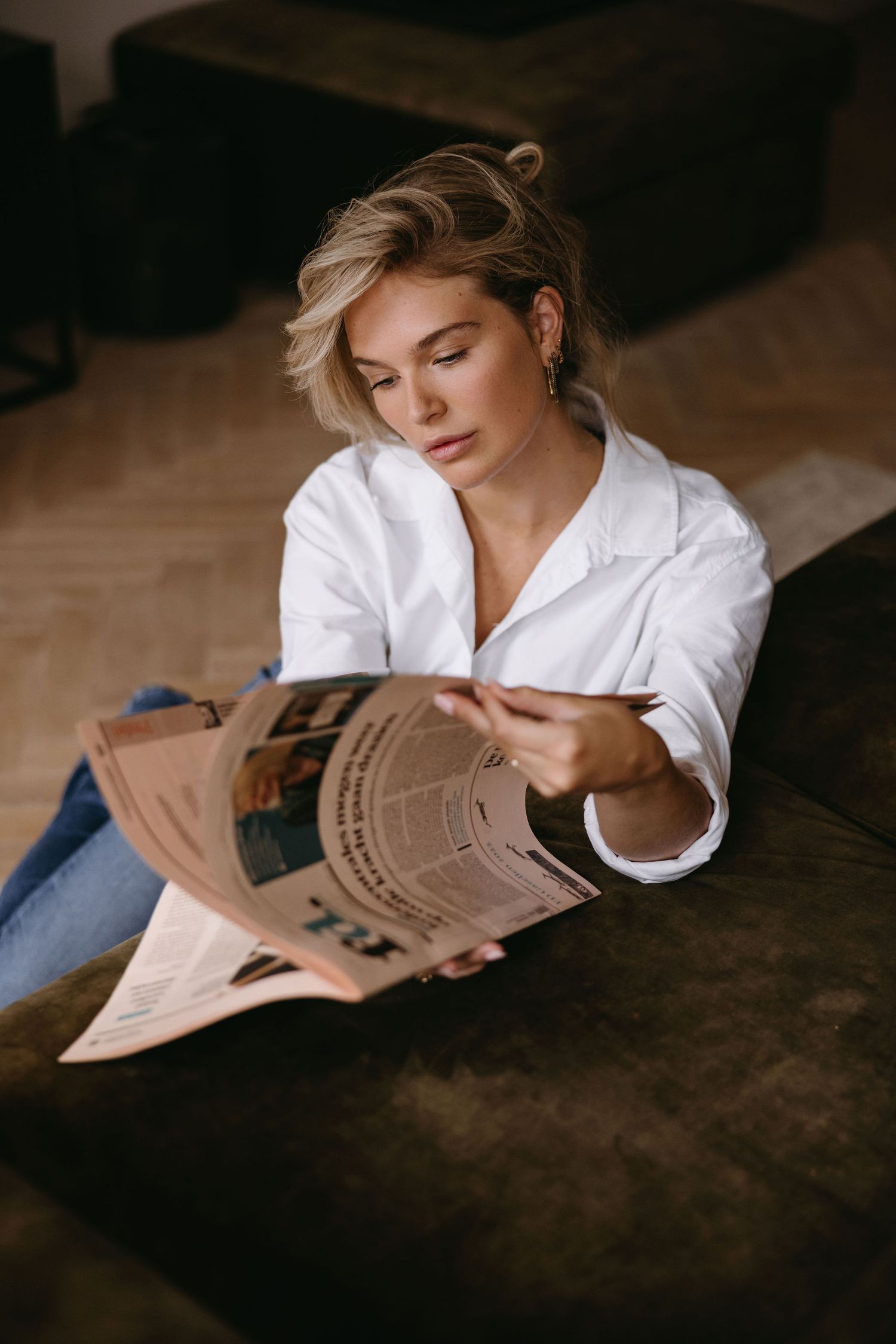 Casual morning scene of reading newspaper while wearing crisp white button-down shirt.