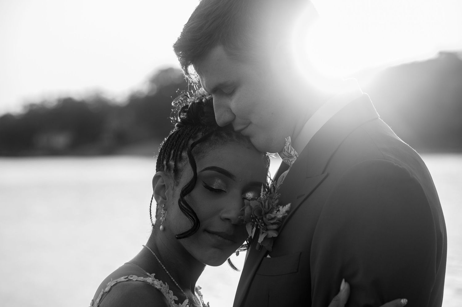 Romantic black and white wedding portrait of newlyweds in soft sunlight.