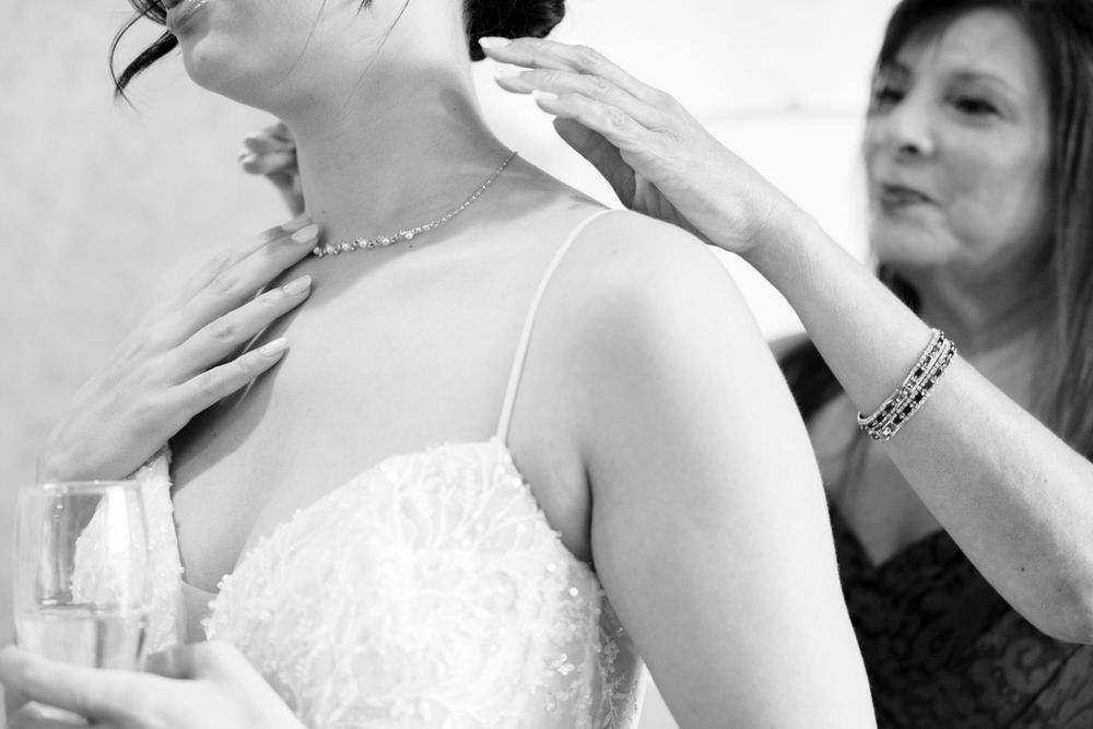 Black and white photo showing final touches being made to wedding dress.