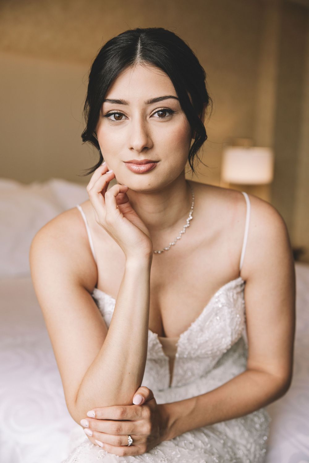 Elegant bridal portrait showing delicate lace dress and jewelry details.