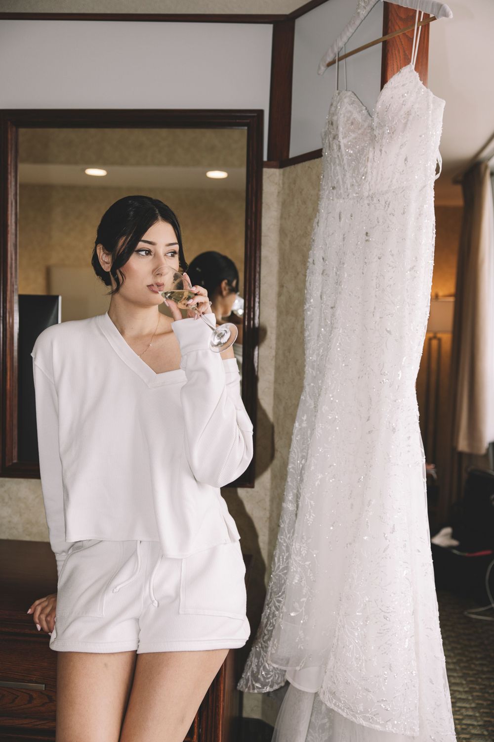 A white wedding dress hangs beside someone wearing a cozy white loungewear set.