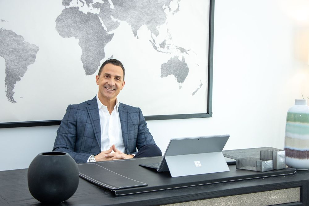 Professional in suit sitting at modern desk with laptop and world map on wall. By NJ Photographer Andrew Fein