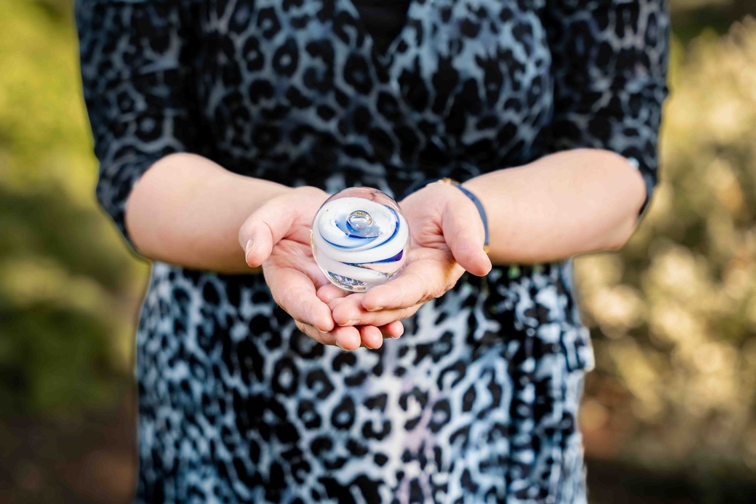 Hands hold a small decorative blue and white ceramic container against a patterned fabric background. Lincolnshire branding photographer.