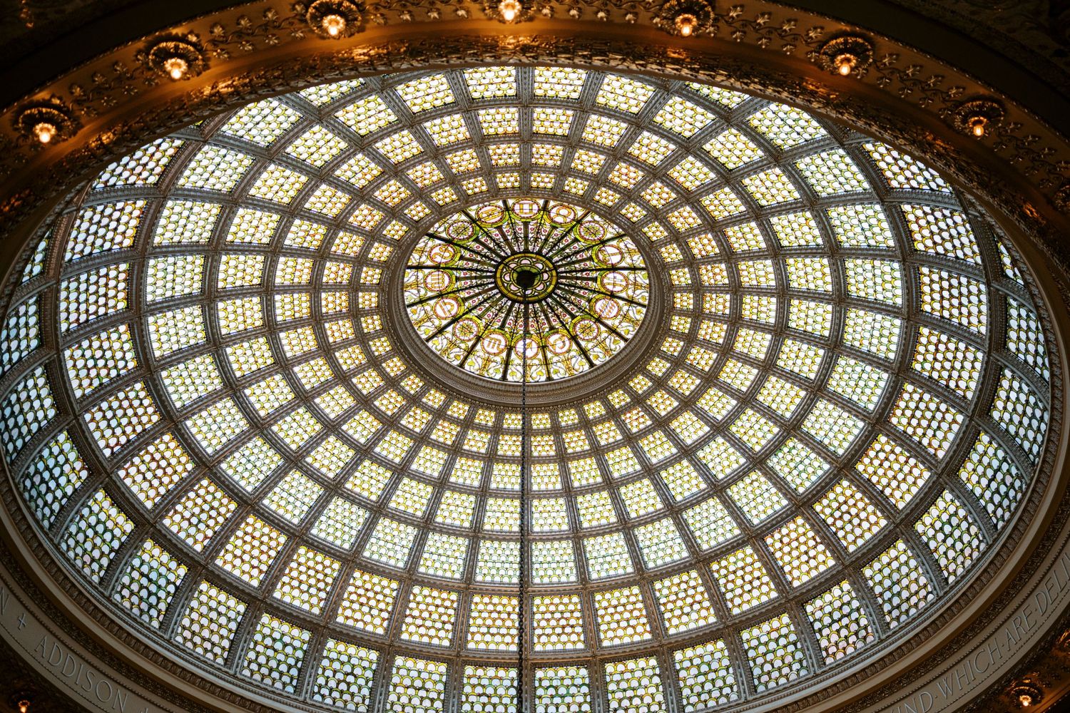 Ornate stained glass dome ceiling with circular pattern and intricate geometric design illuminated from above.