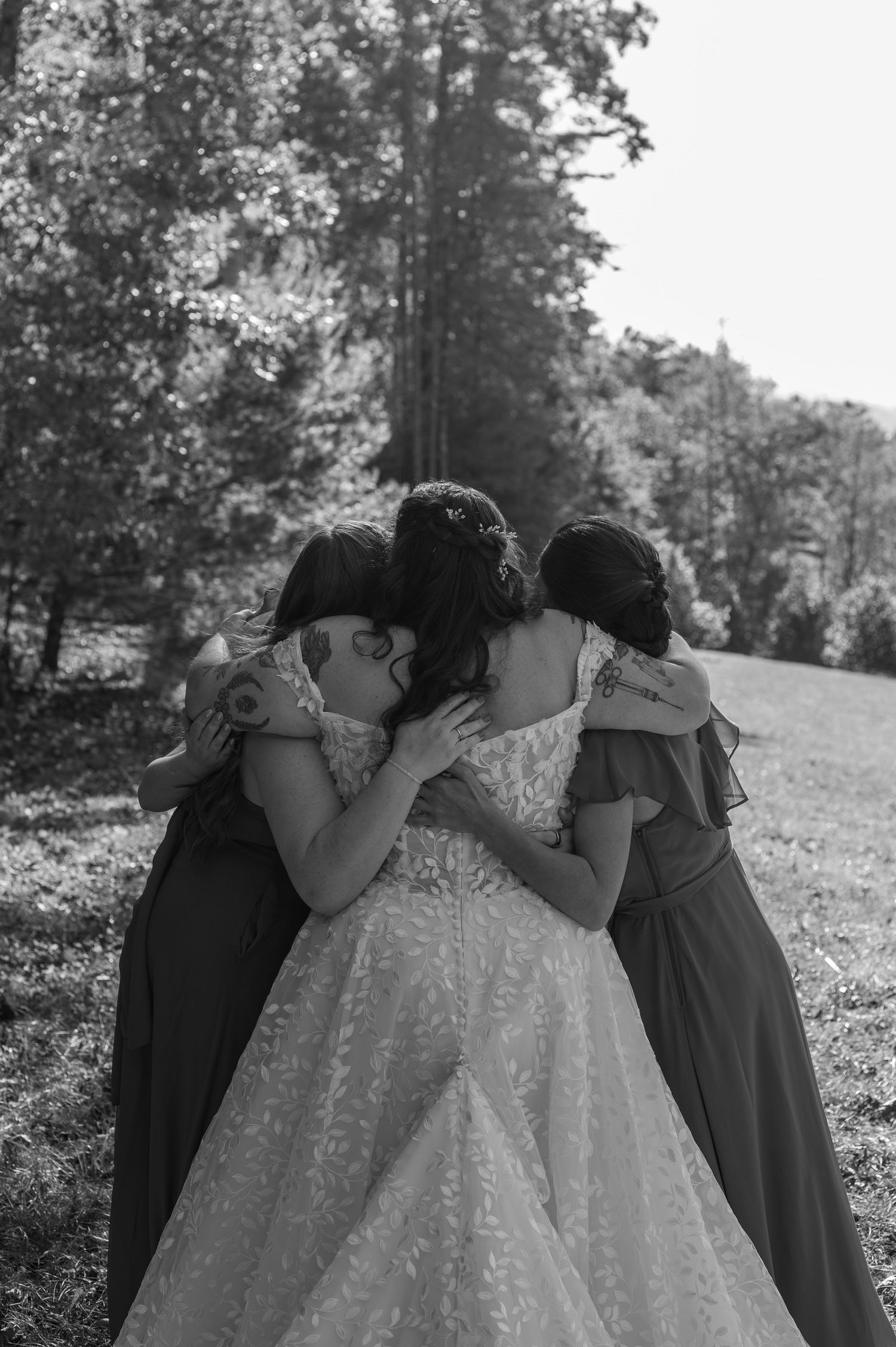 Black and white photo of emotional group hug between bride and bridesmaids.