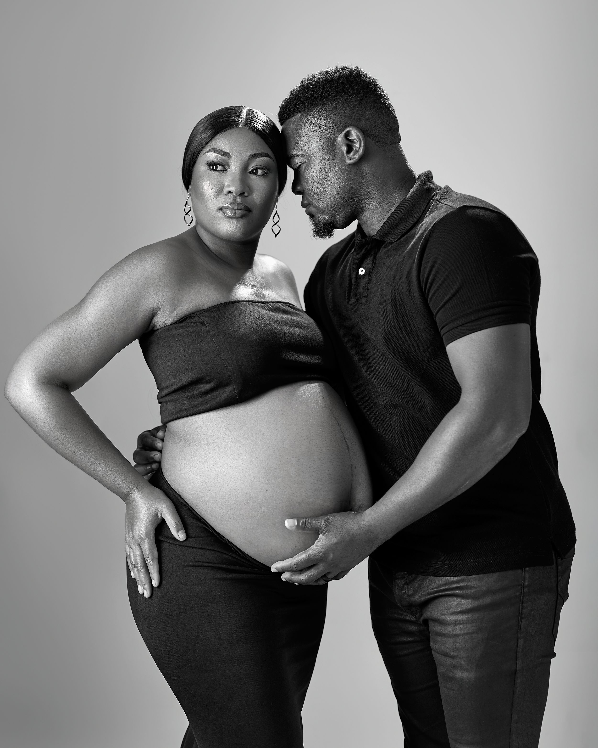 A couple standing for a maternity shoot in black and white