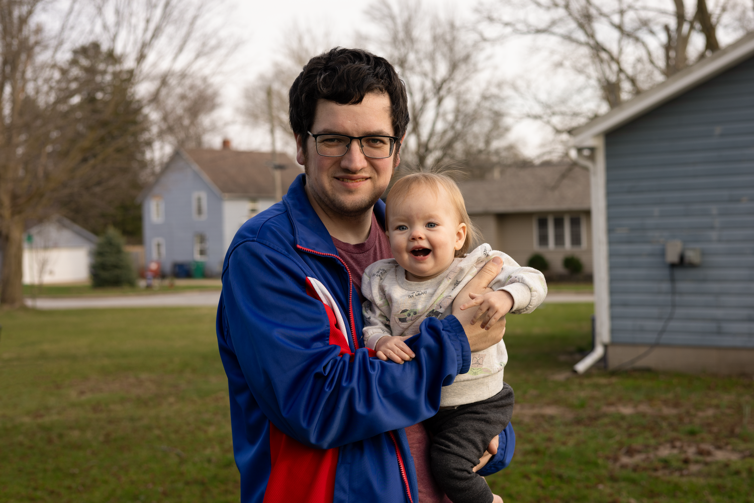 A cheerful outdoor portrait on a spring day in front of a blue house.