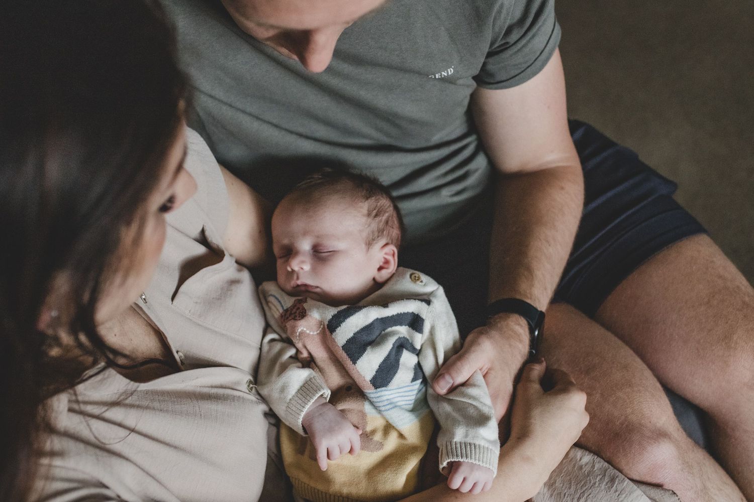 Candid moment of family bonding with infant on couch.