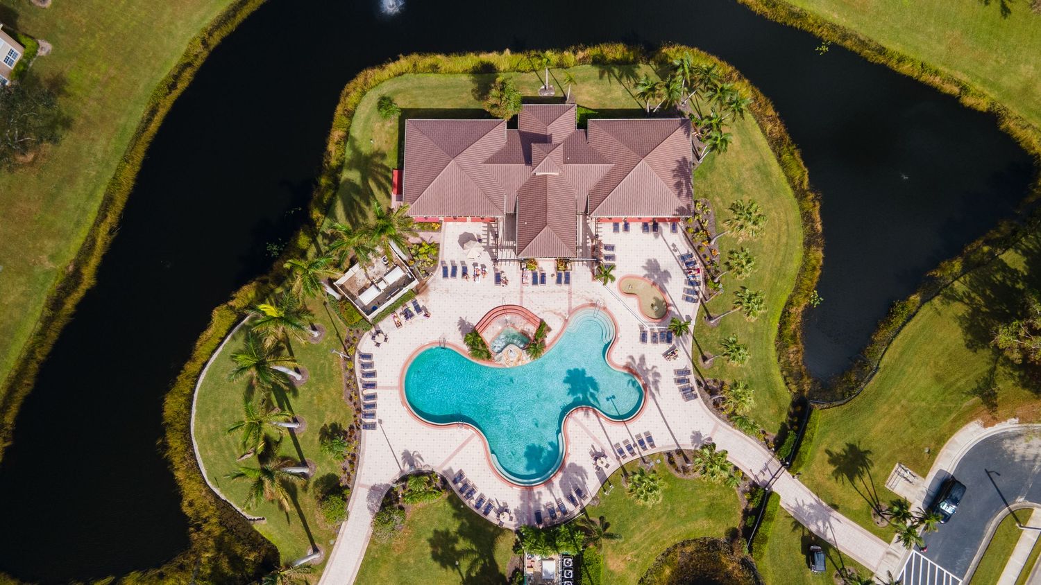 Aerial view of a luxury residential community with a circular lake, fountain centerpiece and palm trees in Florida.