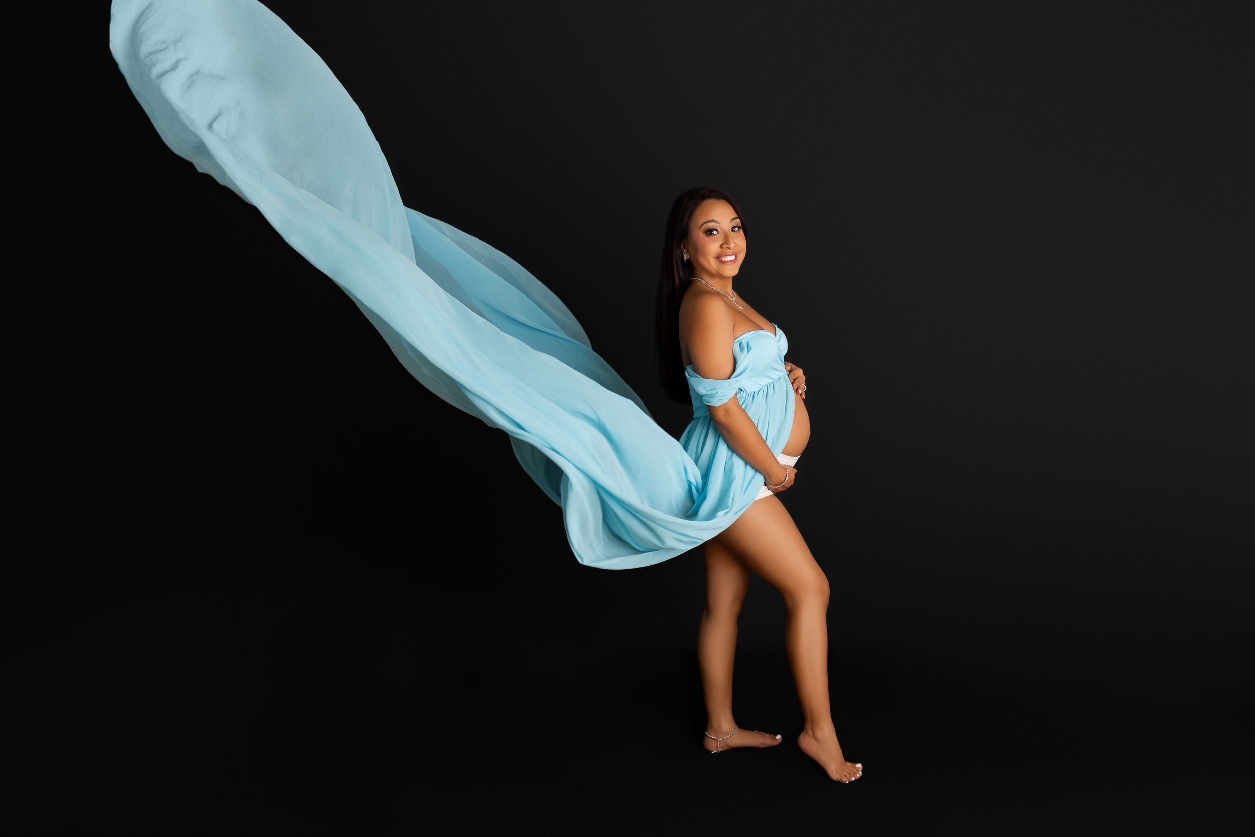 Dancer in light blue flowing fabric performs graceful pose against black background. Sarah Jane Photography LLC Photographer in Sparta NJ