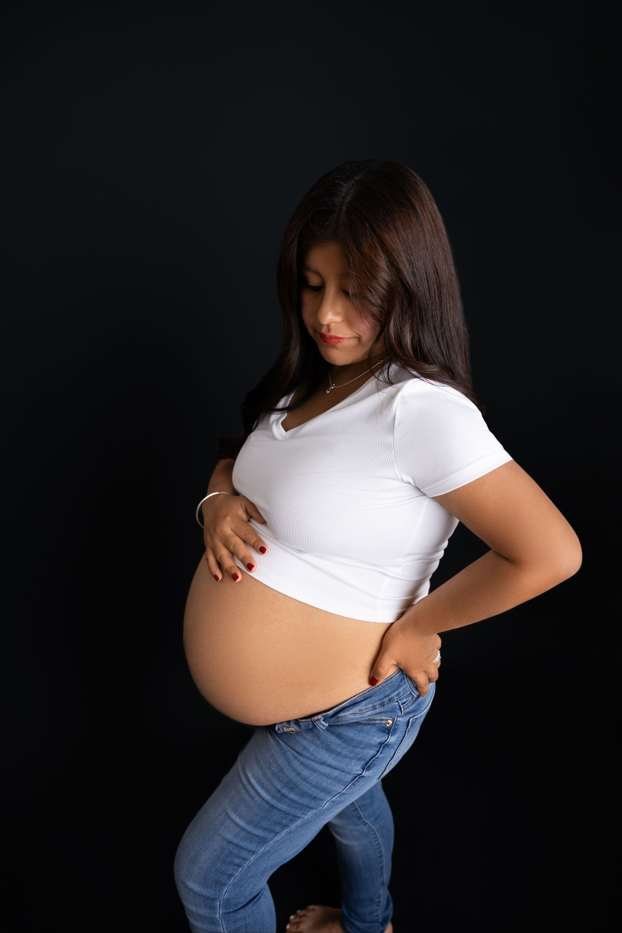 maternity photos showing a pregnant woman's silhouette in white shirt and jeans against a dark background. NJ MATERNITY PHOTOGRAPHER