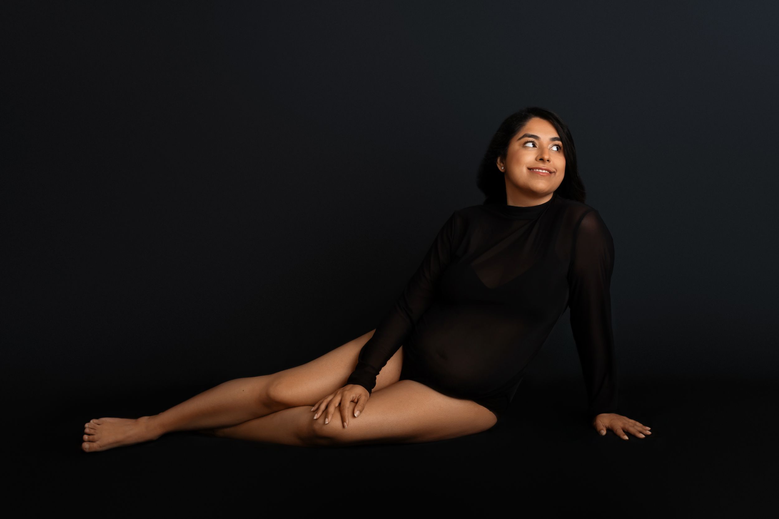 Artistic studio portrait of person in black bodysuit posing gracefully against dark background. Morris County Studio Maternity Photographer
