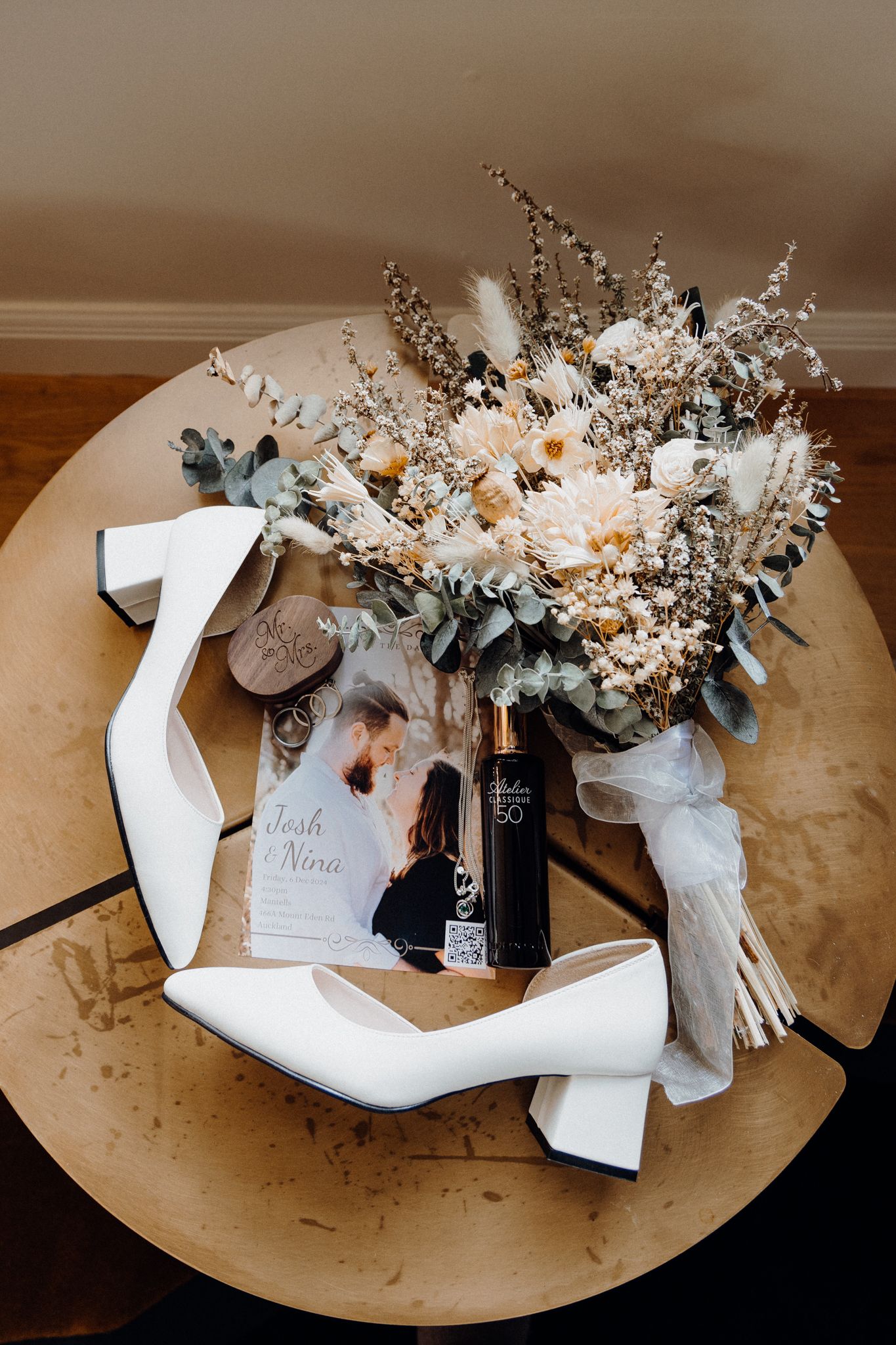 Wedding details flatlay arranged on round wooden table, captured by Apertured Media Auckland Wedding Photographer.