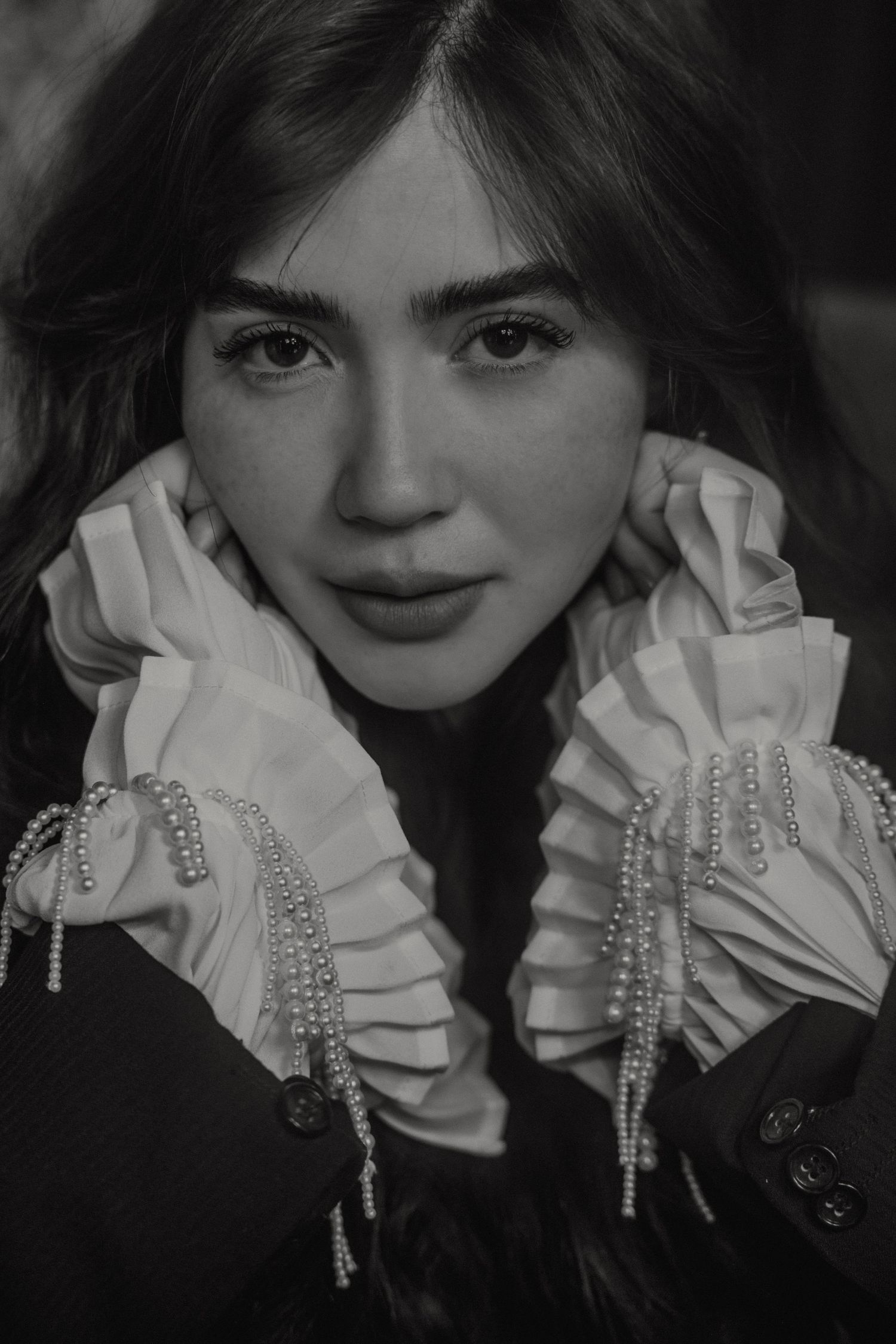 Portrait featuring ornate white ruffled collar with crystal embellishments against dark attire.