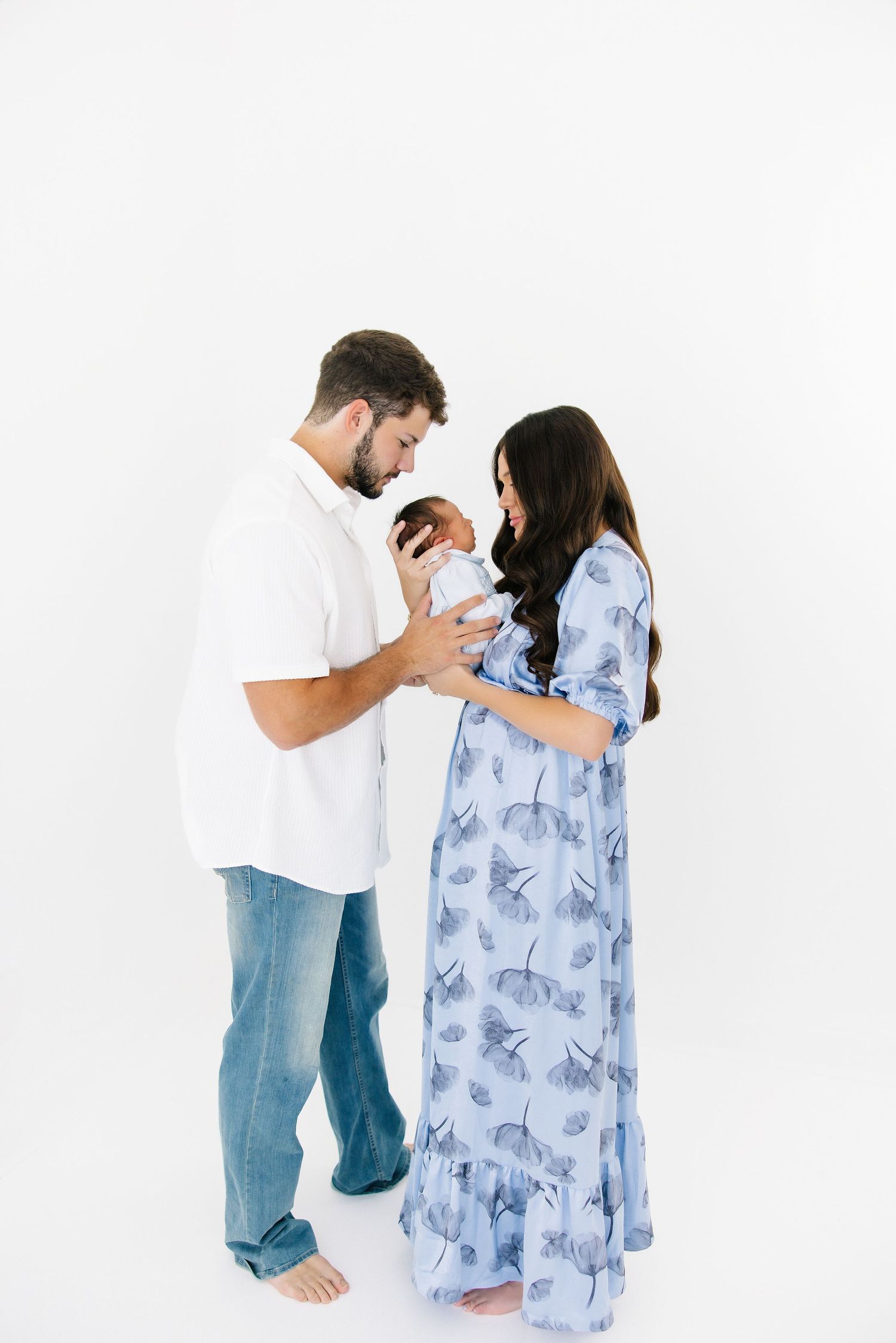 A tender moment between a couple in casual clothing captured against a pure white background.