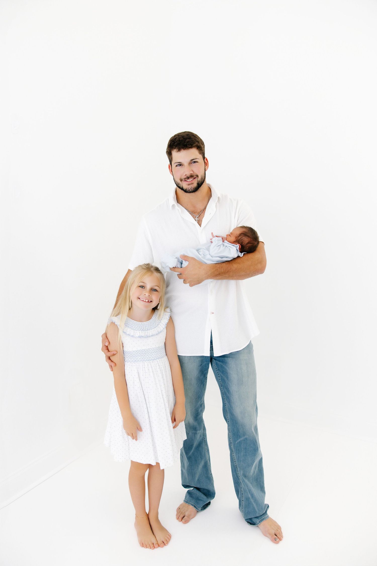A family portrait with parents and children posing playfully against a white background.