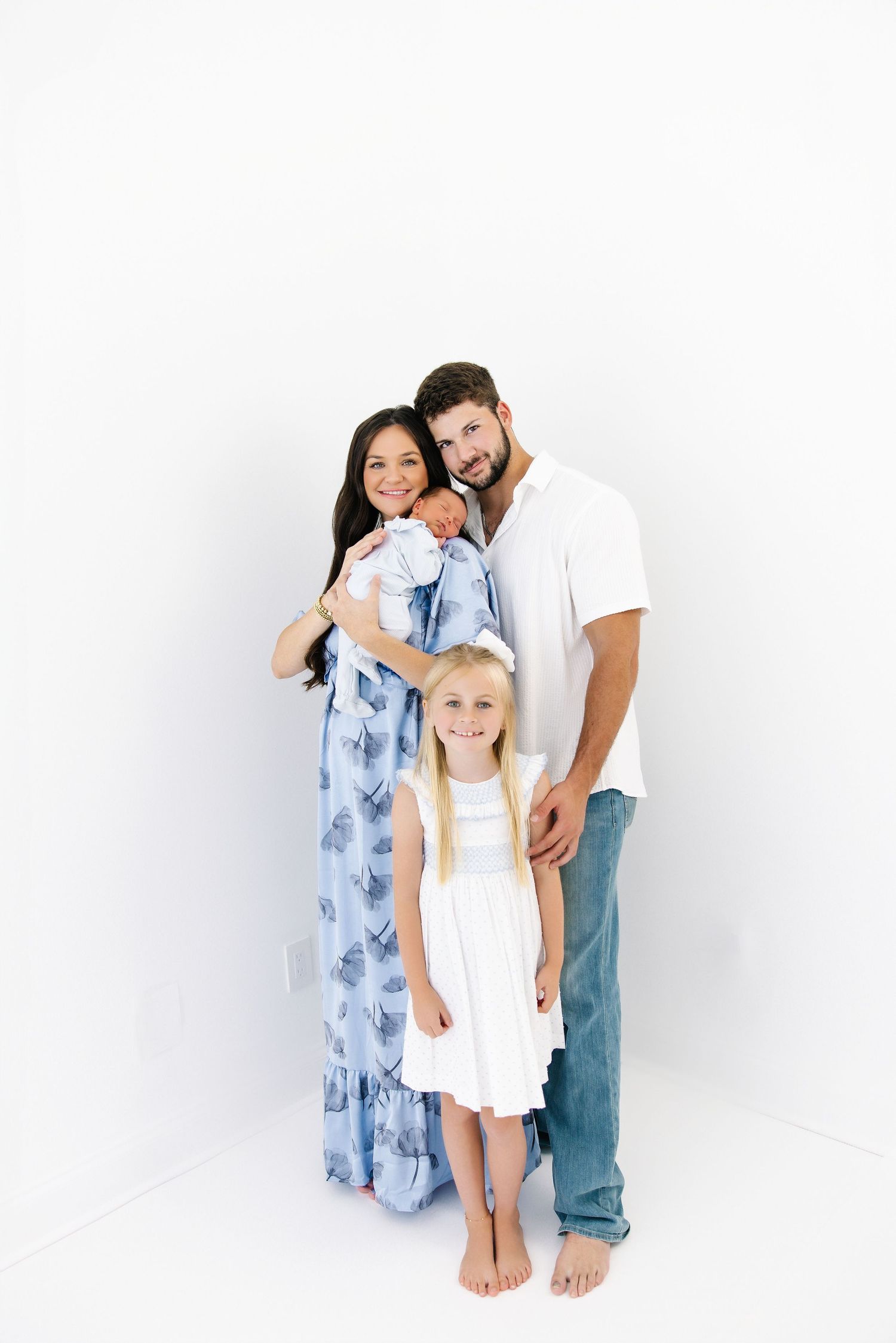 Happy family group poses together against white background in casual clothing.